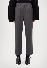 Pantalons gris taille haute avec une coupe décontractée, en tissu tissé. Caractéristiques : taille élastique et jambes droites, associés à des bottines noires.