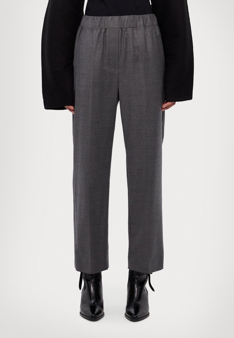 Pantalons gris taille haute avec une coupe décontractée, en tissu tissé. Caractéristiques : taille élastique et jambes droites, associés à des bottines noires.