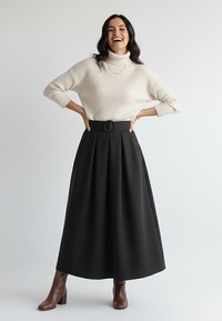 Czarna plisowana długa spódnica z okrągłym paskiem. W połączeniu z kremowym, prążkowanym golfem i brązowymi botkami na obcasie. Gładka faktura.