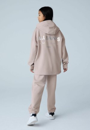 Ensemble sweat à capuche oversize rose clair et jogging assorti, avec un logo argenté au dos, des poignets côtelés et une taille élastique.