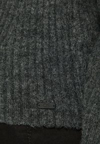 Dunkelgrauer gestrickter Pullover mit geripptem Muster und einem schwarzen QS-Tag. Besteht aus einem weichen, leicht flauschigen Material.