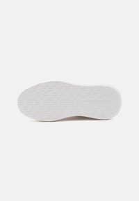 Semelle de chaussure blanche avec motif de bande de roulement géométrique répétitif et texte de marque visible embossé près du talon.