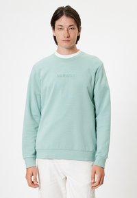 Sudadera verde menta claro con mangas largas, cuello redondo y texto bordado "CONFIDENT" en el pecho. Material suave y liso.
