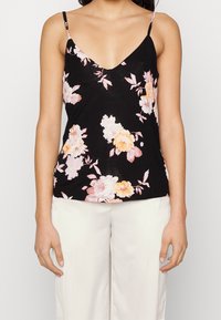 Camisole noire à fleurs avec fines bretelles ; ornée de fleurs roses et blanches sur un tissu doux, avec un décolleté en V profond et une coupe décontractée.