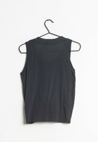 Haut sans manches noir en tissu doux, doté d'un col rond et d'un design simple et ajusté, suspendu sur un cintre en métal noir.