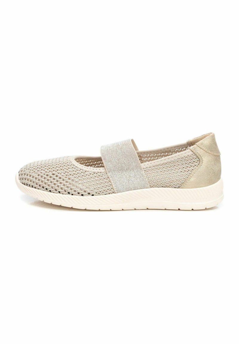 Zapatilla atlética beige con parte superior de malla y una correa brillante. Presenta una suela ligera y flexible con una superficie texturizada para un mejor agarre.