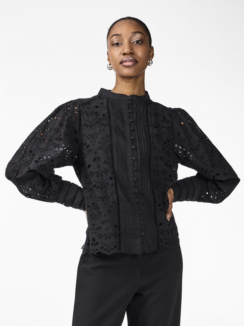 Black embroidered blouse with puff sleeves, featuring button closure, high collar, and intricate cut-out patterns on the fabric.