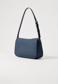 Blue handbag made of textured synthetic material, with a curved shape, a single adjustable strap, and a top zipper closure. Gold hardware accents.