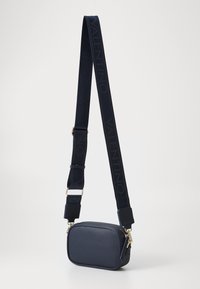 Navy blue leather crossbody bag with a textured finish, featuring a zip closure, gold hardware, and an adjustable strap with logo.
