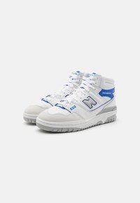 Hvide og blå New Balance høje sneakers med snørebånd, grå såler og "650" trykt nær tåen, vist i en vinkel på en hvid baggrund.