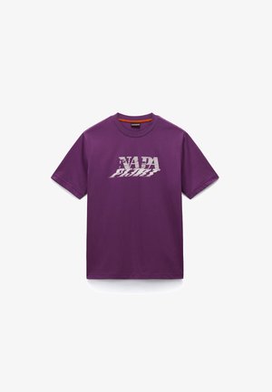Fioletowa koszulka z krótkim rękawem i okrągłym dekoltem, z białym, zdeformowanym napisem "NAPA" na piersi, rozłożona na białym tle.