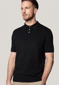 Czarna koszulka polo z krótkim rękawem, z trzema guzikami, ryflowanym kołnierzykiem i dołem, wykonana z lekkiej dzianiny.