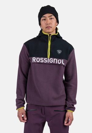Fleece pullover in dark purple and black, featuring a yellow zipper and "ROSSIGNOL" logo across the chest. Soft texture with long sleeves.