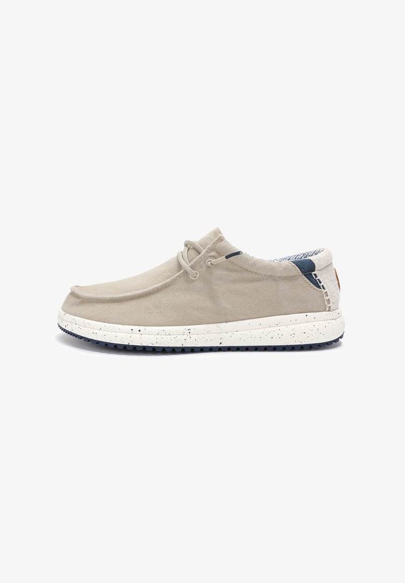 Beige canvas shoe with a round toe, elastic laces, and a speckled white sole. Blue accents on the heel and patterned lining visible inside.