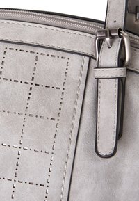 Grijze faux leren tas met een gequilt patroon, een soepele textuur, contrasterende stiksels en metalen hardware met een ritssluiting.