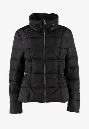 Woman walking wearing a black puffer jacket, light pink top, blue skinny jeans, black ankle boots, and carrying a black bag on shoulder.