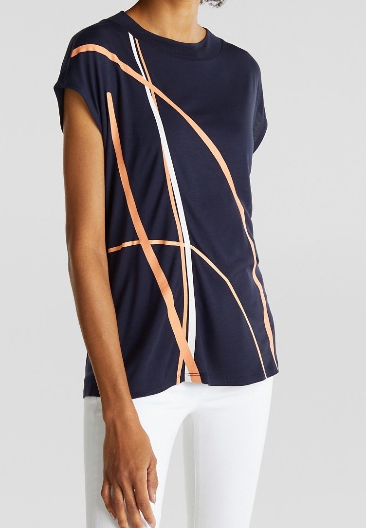 Marintröja med kort ärm i abstrakta linjer i orange och vitt. Mjukt tyg, avslappnad passform, rund halsringning. Bärs med vita byxor.