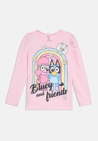Różowa koszulka z długim rękawem z grafiką postaci z kreskówek na tle tęczy i kwiatów. Napis głosi „Bluey i przyjaciele.”