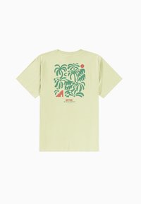 Camiseta de manga corta color verde claro con un gráfico de hoja de palma en verde y rojo, con texto debajo en la parte posterior. Material de algodón.