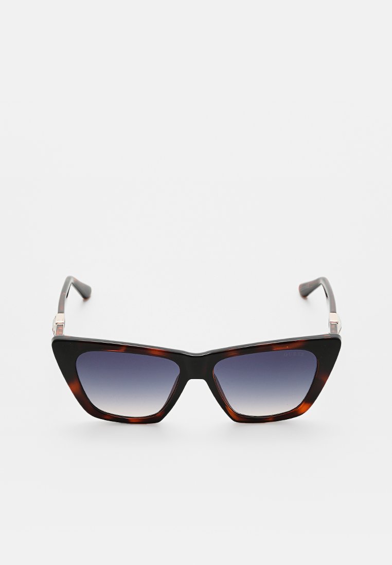 Lunettes de soleil en forme d'yeux de chat avec une monture noire et écaille de tortue, des verres gris dégradés et des accents argentés sur les branches.