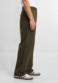 Olijfgroene broek met een rechte pijpdesign, gemaakt van een gladde stof. Voorzien van zijzakken en een knoopdetail bij de taille.