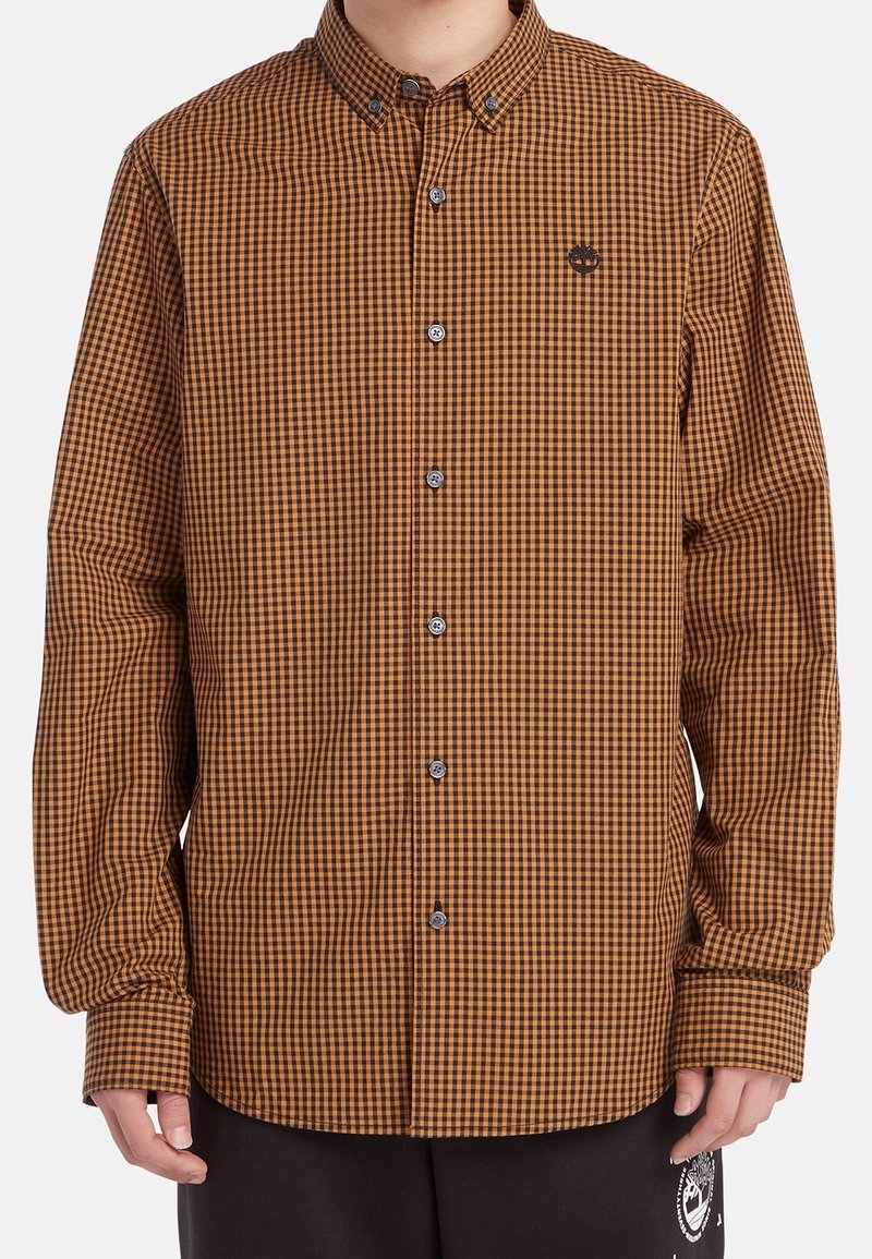 Chemise à carreaux marron et noir à manches longues avec boutons, col boutonné et petit logo brodé sur la poitrine gauche.