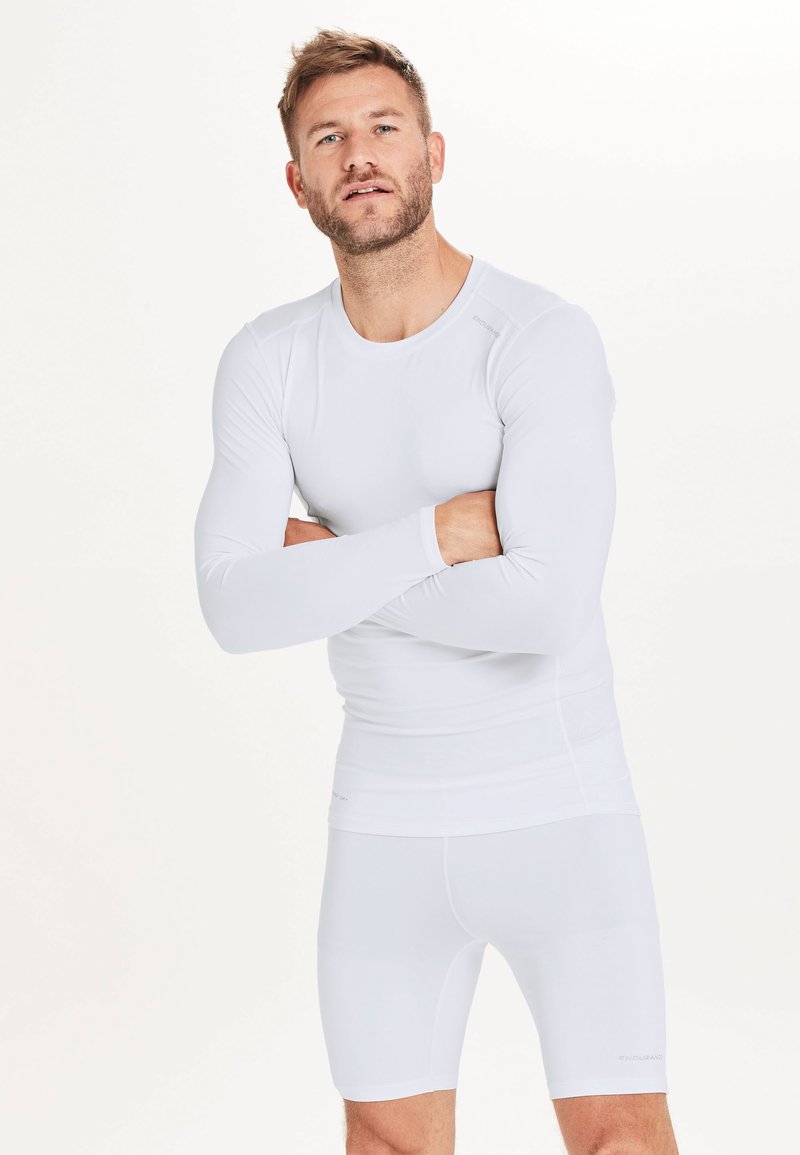 Witte sportieve longsleeve top met een ronde hals en een slim fit ontwerp, gecombineerd met bijpassende strakke shorts. Gemaakt van rekbare, gladde stof.