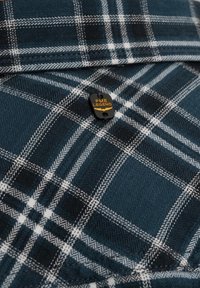 Donkerblauw flanellen overhemd met een wit en grijs ruitpatroon. Heeft een zwart etiket met gele tekst "PME LEGEND." Zachte textuur, gevouwen ontwerp.