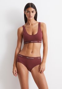 Bordeaux beha en slipset vervaardigd uit een zachte stof met een brede elastische band die het "Marc O'Polo" logo in contrasterende kleur toont.