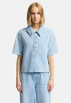 Lichtblauwe denim shirt met een grote kraag, korte mouwen, een vijfknopenlijst en een verkort hem. Zachte textuur met subtiele vervaging.