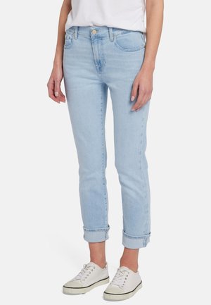 Helle blaue Jeans aus Denim, mit Slim-Fit und umgeschlagenen Säumen, Fronttaschen und Knopfverschluss. Getragen mit weißen Sneakers.