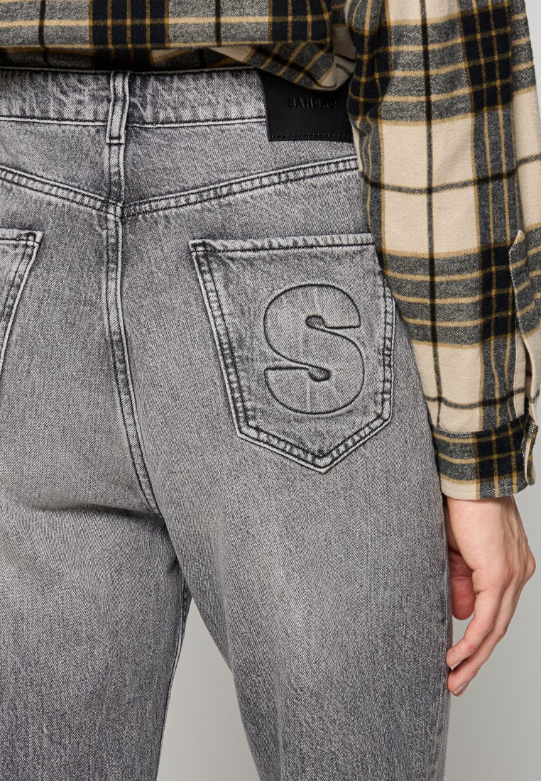 Szare dżinsy z lekko wypłowiałym wykończeniem, z tylnymi kieszeniami z wytłoczonym liścikiem "S" oraz czarną metką na pasku.