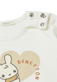Weißes Baumwoll-T-Shirt mit einem Comic-Hasen-Design in einem beigen Herz, mit dem Text "BENETTON" in Orange. Mit Druckknöpfen an der Schulter.