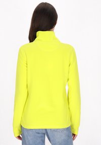 Gul fleecepullover med høj krave, lange ærmer og en glat tekstur. Har et rent design på bagsiden og en let tætsiddende form.
