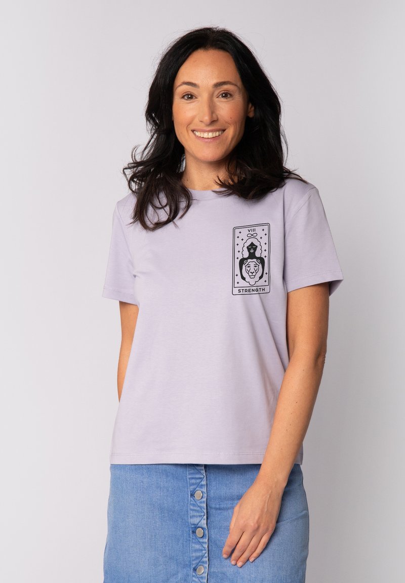 T-shirt en coton violet clair avec un col rond et des manches courtes. Présente un imprimé graphique noir d'une femme et d'un lion, étiqueté "FORCE".