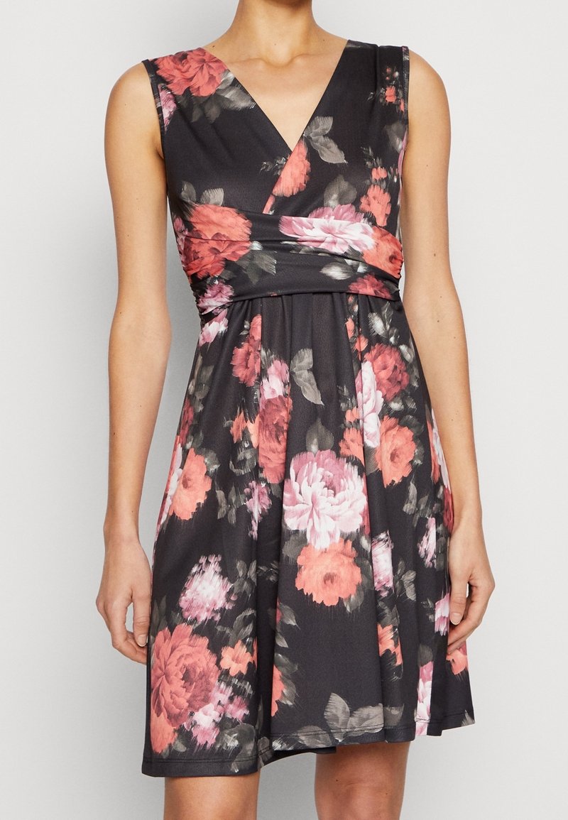 Blommig klänning med svart bakgrund, rosa och korallfärgade rosor, V-ringning och en insydd midja med design av utsvängd kjol.