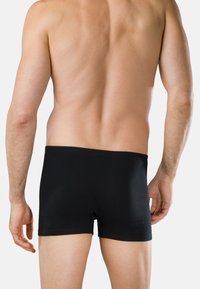 Czarne bawełniane bokserki z szerokim, elastycznym pasem, dopasowanym krojem i gładką fakturą, widoczne od tyłu na neutralnym tle.