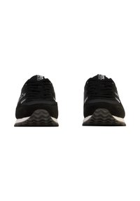 Chaussures de sport noires avec une tige en daim et en mesh, dotées d'une semelle à motif zigzag, de lacets et d'un petit logo sur la languette.