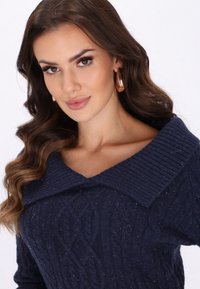 Dunkelblauer gestrickter Pullover mit geripptem Kragen, der ein strukturiertes Zopfmuster aufweist und eine lockere Passform hat, aus weichem Material gefertigt.