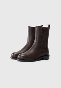 Brown leather ankle boots with a smooth finish, elastic side panels, and a low square heel. Features a rounded toe and stitching detail.