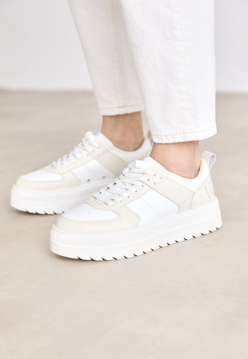 Białe i kremowe sneakersy z teksturowaną podeszwą, z perforowanymi akcentami, sznurowanym designem oraz wyściełanym kołnierzem dla komfortu.