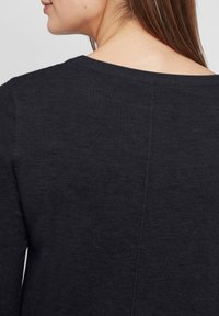Maglione grigio scuro lavorato a maglia con scollatura rotonda, tessuto texturizzato e una cucitura centrale sul retro. Design semplice senza decorazioni.