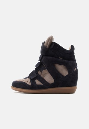 Sneaker a zeppa alta con pannelli in suede nero e beige, tre cinturini regolabili e suola in gomma marrone.