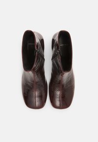 Burgunderfargede ankelboots med en skinnende, strukturert finish, som har en sidelukking og en glatt, avlang form. Klare sømmer langs skjøtene.