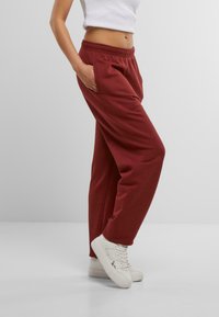 Bordo sporta bikses, izgatavotas no mīksta auduma, ar elastīgu jostu un sānu kabatām, savienotas ar baltām kedām. Mākonīša priekšpuse un brīvs piegriezums.