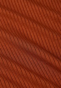 Textil in tiefem Orange mit gerippter Textur, die erhöhte vertikale Linien zeigt. Weiches, flexibles Material mit einer glatten Oberfläche.