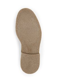 Semelle de chaussure en matériau en caoutchouc texturé de couleur brun clair, avec un bout rond et un talon plat. La surface présente un motif légèrement rugueux.