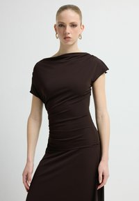 Brązowa dopasowana sukienka z krótkimi rękawkami typu cap, marszczonym wzorem i dekoltem w kształcie draperii. Gładka tkanina o smukłej sylwetce.
