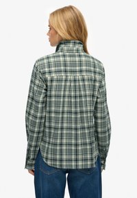 Groen en crème geruit overhemd met een hoge kraag, lange mouwen en een licht gebogen zoom. Gemaakt van zachte stof met een losse pasvorm.