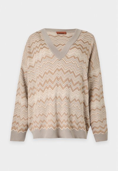 Pull beige et crème à manches longues avec col en V, motif en zigzag, poignets et ourlet côtelés.